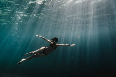 Frau schwimmt in voller Länge unter Wasser im Ozean - CAVF63538