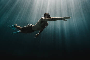 Ein Mann schwimmt in voller Länge unter Wasser im Ozean - CAVF63539