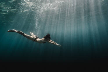 Frau schwimmt in voller Länge unter Wasser im Ozean - CAVF63540