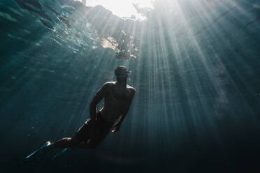 Ein Mann schwimmt in voller Länge unter Wasser im Ozean - CAVF63541