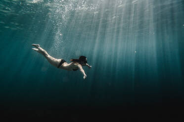 Frau schwimmt in voller Länge unter Wasser im Ozean - CAVF63543