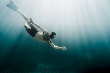 Full length of man swimming underwater in the ocean - CAVF63544