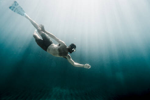 Mann schwimmt in voller Länge unter Wasser im Ozean - CAVF63544