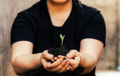 Adults hold small trees. Earth Day is environmentally friendly. - CAVF63571