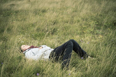 Young woman lying in the grass daydreaming. - CAVF63640