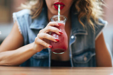 Hübsche Frau mit roten Lippen trinkt einen Cocktail Soda - CAVF63645