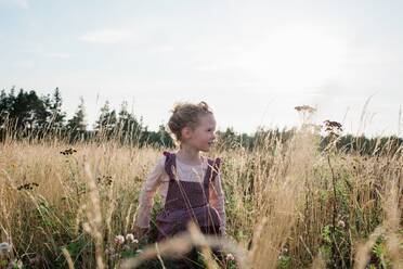 Porträt eines jungen Mädchens auf einer Wiese bei Sonnenuntergang im Sommer - CAVF63670