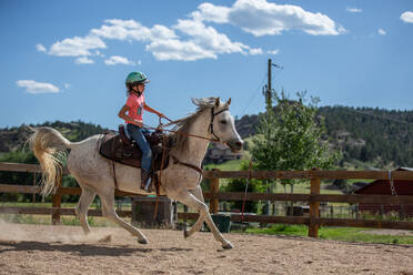 Mädchen reitet auf einem Pferd in einer Reithalle - CAVF63681