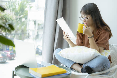 Teenager-Mädchen mit Tablet und entspannt auf dem Stuhl in der Co-Worki - CAVF63715