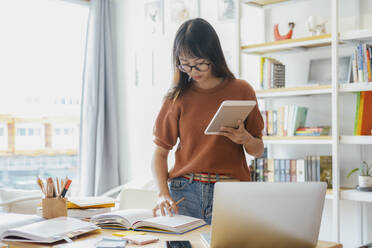 Junger Collegestudent mit Computer und mobilem Gerät beim Lernen - CAVF63725