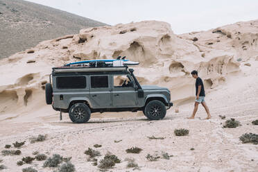 Junger Mann geht außerhalb des 4x4 beim Camping - CAVF63750