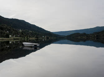 Blick auf Berge und See mit einem weißen Ruderboot in Norwegen - CAVF63872