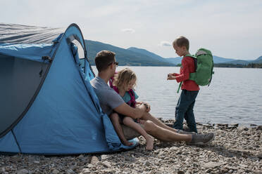 Familie umarmt und erkundet Camping am Wasser in Norwegen - CAVF63875