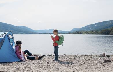 Sohn fotografiert Mutter und Tochter beim Zelten am Strand - CAVF63884