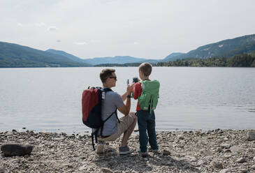 Vater und Sohn fotografieren mit Handys die Berge - CAVF63888