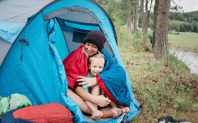 Mutter und Sohn saßen lächelnd in einem Zelt beim Camping im Urlaub zusammen - CAVF63915