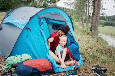 Porträt von Mutter und Sohn lächelnd umarmend in einem Zelt beim Camping - CAVF63916