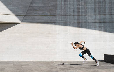 Gezogene Rückansicht einer Sportlerin beim Laufen auf Beton - CAVF63987
