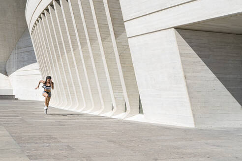 Gezogene Rückansicht einer Sportlerin beim Laufen auf Beton - CAVF63993
