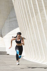 Full body of female athlete in sportswear running on concrete - CAVF63994