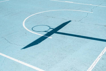Schatten eines Basketballkorbs auf einem bunten Platz - CAVF63999