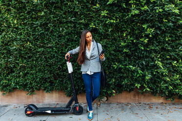 Woman Looks at Phone with Scooter - CAVF64063