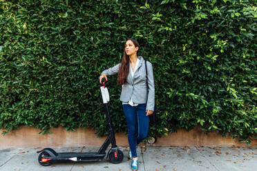 Woman Stands Next to Electric Scooter - CAVF64064