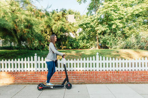 Woman Rides Scoot on Sidewalk - CAVF64069