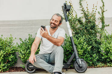 Man Smiles with Phone and Scooter - CAVF64082