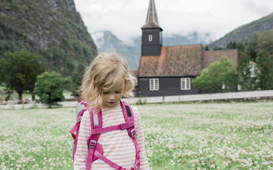Girl backpacking outside a beautiful church & fjord in Fl√§m, Norway - CAVF64094