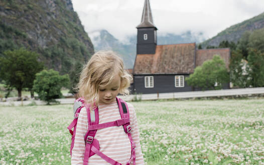 Mädchen auf Rucksacktour vor einer schönen Kirche und einem Fjord in Fl√§m, Norwegen - CAVF64094