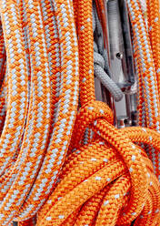Segelnde orangefarbene Seile, die an einem Mast auf einer Yacht befestigt sind - CAVF64106