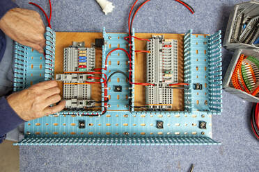 Ein Schiffselektriker bei der Arbeit an einer elektrischen Schalttafel in einer Werkstatt - CAVF64119