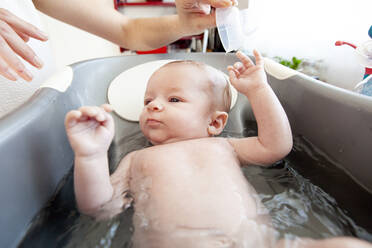A baby girl having a bath in a kitchen, Lomener, Brittany, France. - CAVF64134