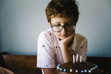 Ein kleiner Junge bewundert seine Geburtstagstorte, nachdem er sie verziert hat. - CAVF64171