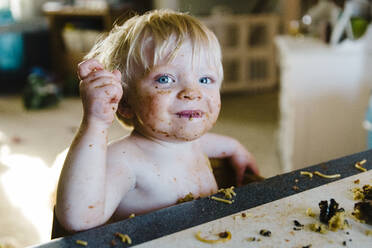 Toddler at table with huge dinner mess in front of him and on face. - CAVF64174