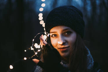 Close up Porträt der schönen jungen Frau hält Weihnachtsbeleuchtung - CAVF64259