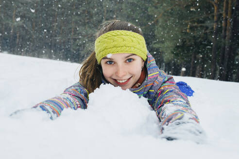 Mädchen liegt im Schnee und lächelt - CAVF64272