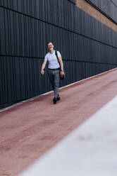 Mature bearded businessman with shoulder bag in the city - CAVF64312