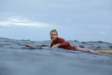 Mann auf Surfbrett auf dem Meer liegend - CAVF64314