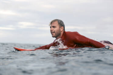 Mann auf Surfbrett auf dem Meer liegend - CAVF64315