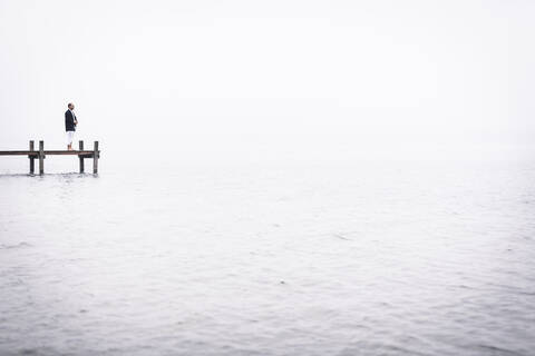 Barfuß meditierender Mann am Steg des Starnberger Sees, Deutschland, lizenzfreies Stockfoto