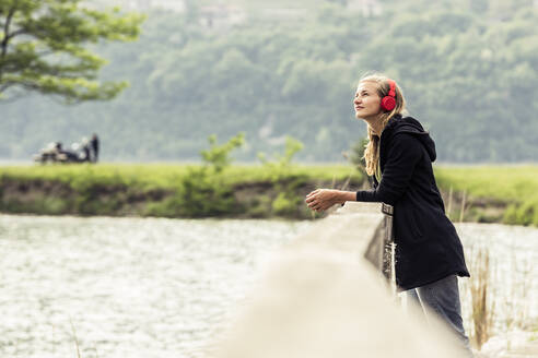 Young woman with red headphones relaxing at Lake Idro, Baitoni, Italy - WFF00103