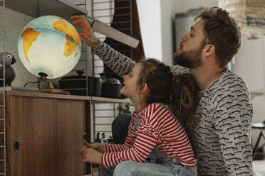 Girl with father looking at globe - JOHF01996