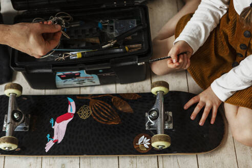 Father and daughter checking skateboard wheels - JOHF02014