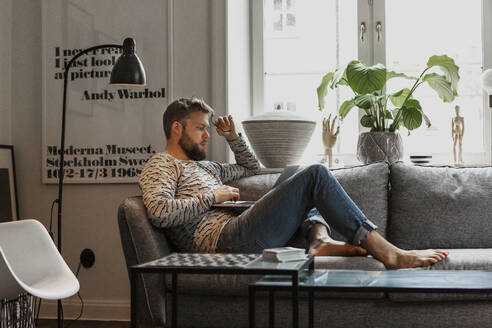 Man on sofa using laptop - JOHF02021