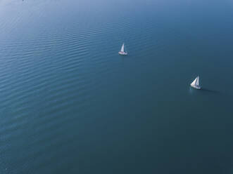 Germany, Bavaria, Aerial view of two sailboats sailing across blue waters of Chiemsee lake - MMAF01152