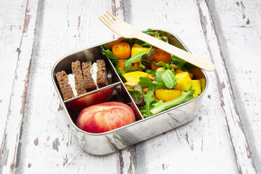 Close-up of lunchbox with mango salad, rye bread sandwich and peach - LVF08299