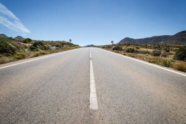 Spanien, Andalusien, Cabo de Gata, Abnehmende Perspektive der leeren Landstraße an einem sonnigen Tag - EGBF00313