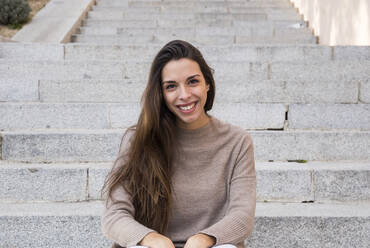 Porträt einer lächelnden Frau, die auf einer Treppe in Boadilla del Monte sitzt - CAVF64410
